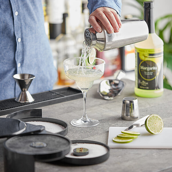 A man using the Choice Margarita Starter Kit to pour a drink into a glass.