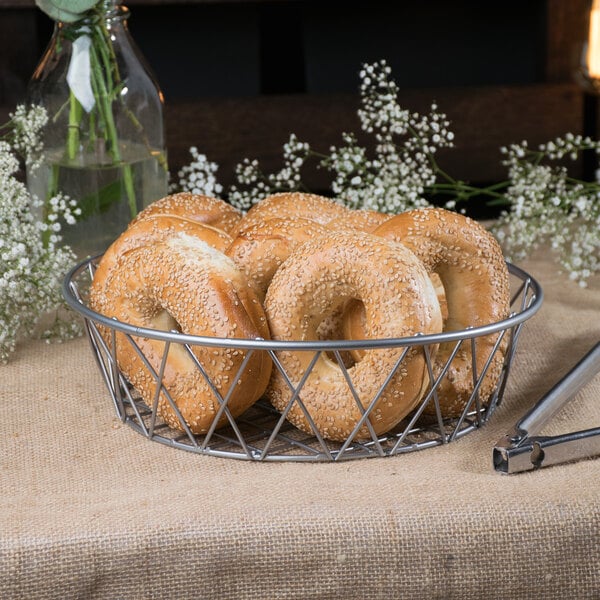 A gray Clipper Mill iron wire basket filled with bagels on a table.