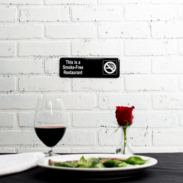 A plate of food and a rose on a table with a black and white smoke-free restaurant sign.