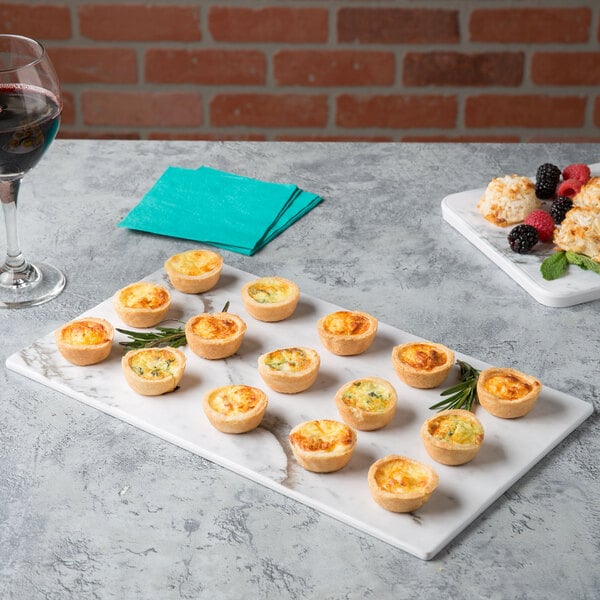A Thunder Group white faux marble melamine serving board with mini quiches.