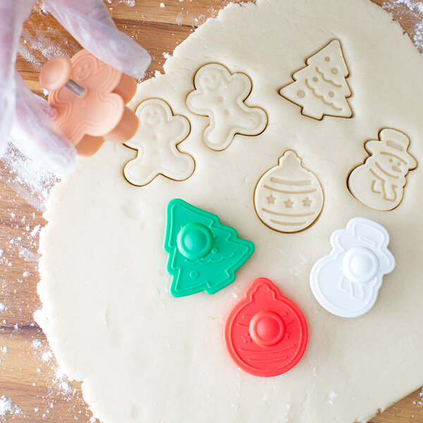A person's hand using an Ateco Christmas cookie plunger cutter.
