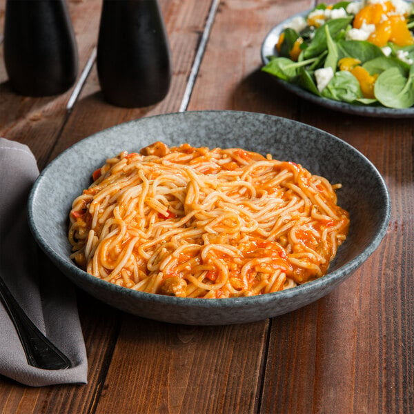 A Biseki blue stoneware pasta bowl filled with spaghetti and salad.