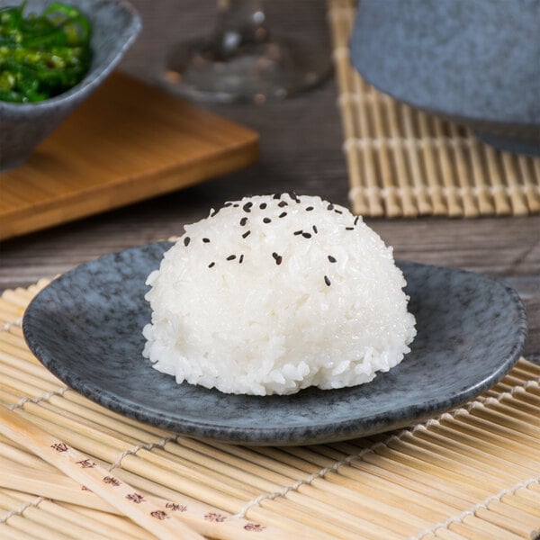 A rectangular blue stoneware plate with rice and black sesame seeds on it.