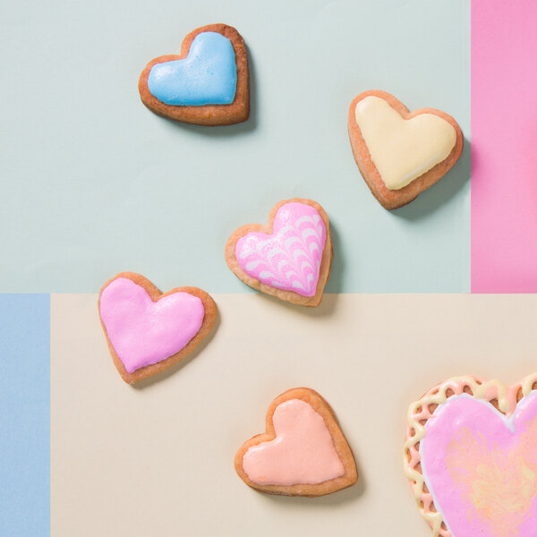 A group of heart shaped cookies with blue, pink, and white frosting.