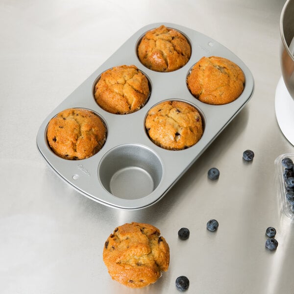 A Wilton jumbo muffin pan with blueberries on a table.