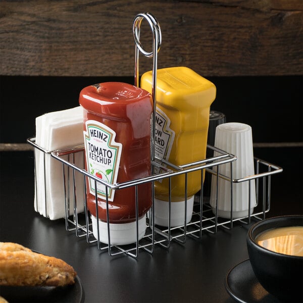 A Clipper Mill metal condiment caddy holding 4 condiments on a table in a hotel buffet.