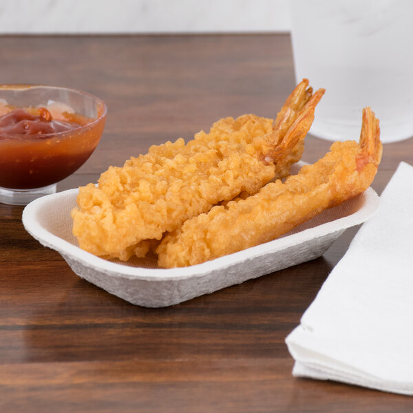 A Huhtamaki Chinet rectangular paper food tray of fried shrimp next to a bowl of sauce on a counter.