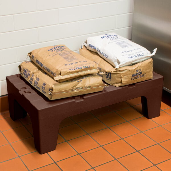 A brown Cambro dunnage rack with bags of salt on it.