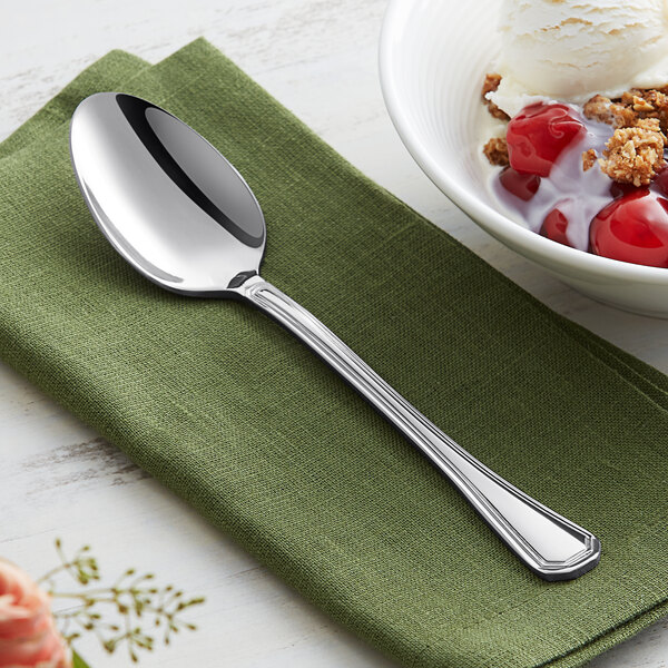 An Acopa Landsdale stainless steel spoon on a napkin next to a bowl of cherry crumble and vanilla ice cream.