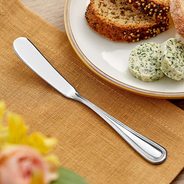An Acopa Edgeworth butter knife on a plate with butter.