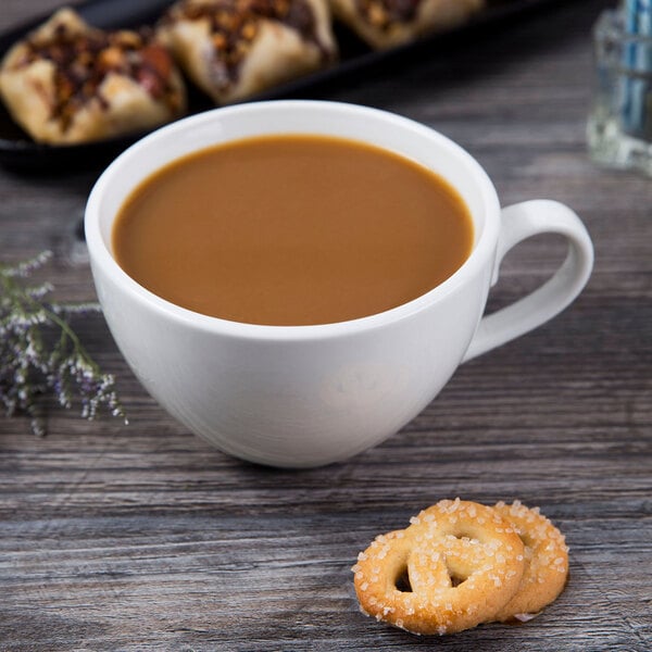 A Libbey bright white porcelain low cup of coffee with cookies on a table.