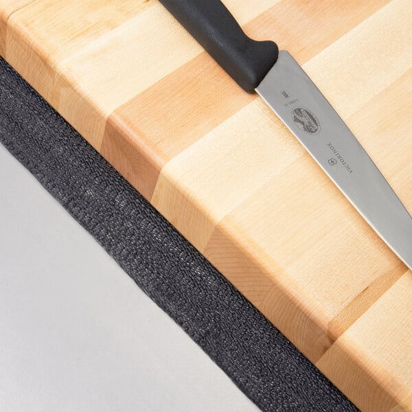 A Board Buddy non-slip cutting board mat with a knife on it.