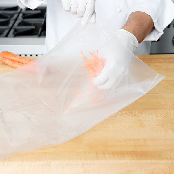 A person in white gloves using an ARY VacMaster plastic bag to vacuum pack carrots.