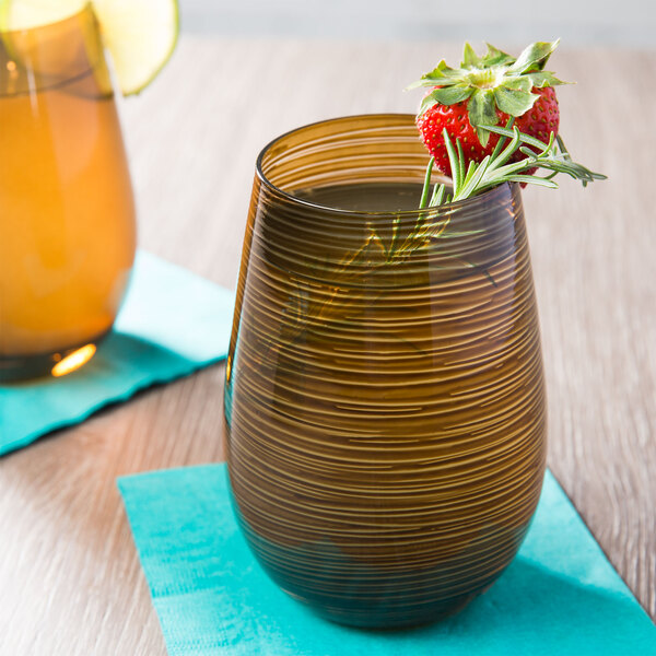 A Stolzle stemless wine glass with strawberries and a rosemary sprig on a table.