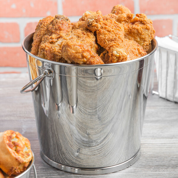 A Clipper Mill stainless steel serving bucket filled with fried chicken and other food.
