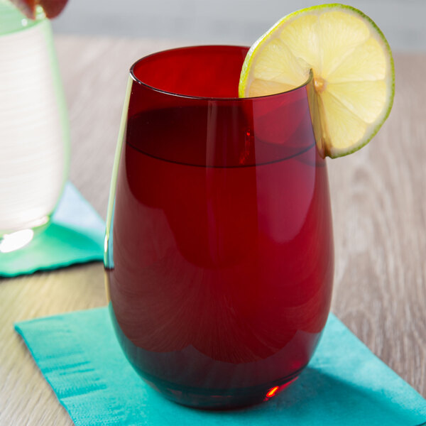 A red Stolzle stemless wine glass filled with red liquid and a slice of lime.