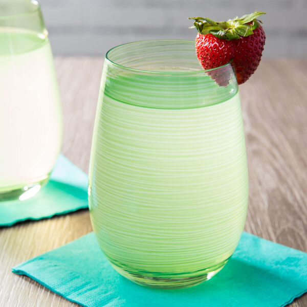 A close up of a Stolzle green stemless wine glass filled with green liquid and a strawberry.