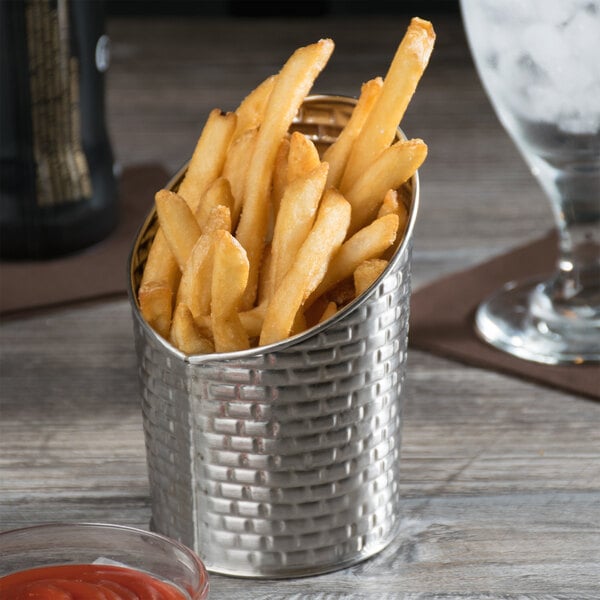 A Tablecraft stainless steel round fry cup filled with french fries on a table with ketchup.
