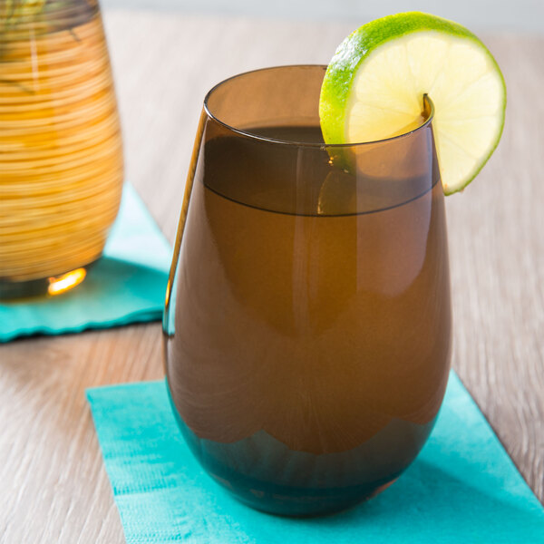 A Stolzle brown stemless wine glass with brown liquid and a lime wedge.