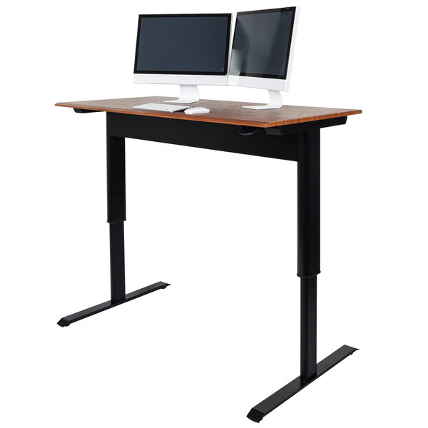 A Luxor pneumatic adjustable height standing desk with a computer and two monitors on it.