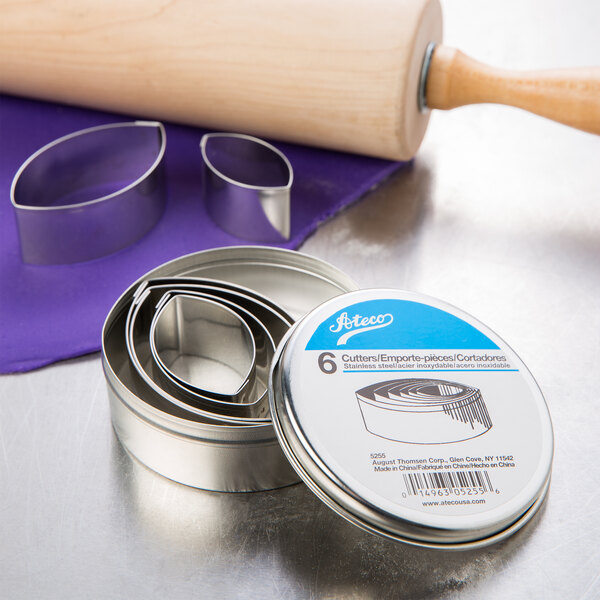 A metal tin with Ateco stainless steel football cookie cutters and a rolling pin.