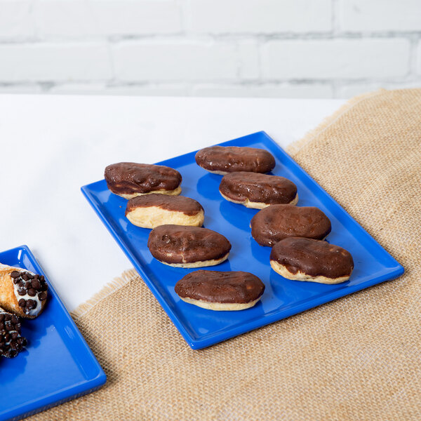 A chocolate covered doughnut on a Tablecraft cobalt blue rectangular cooling platter.