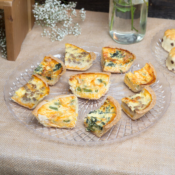 A piece of quiche on a Fineline clear plastic catering tray.