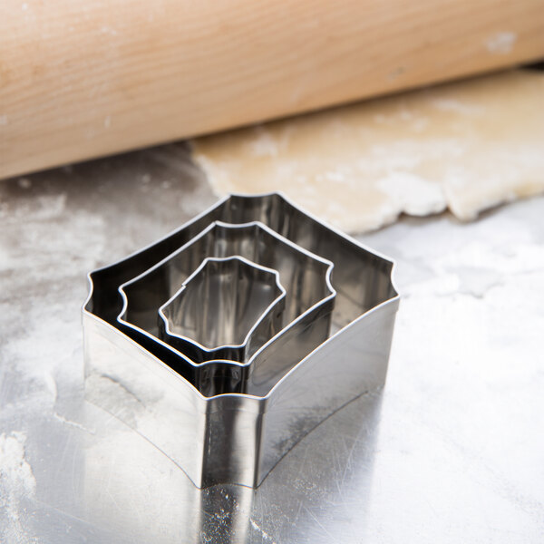 A set of Ateco stainless steel plaque cookie cutters on a wood table.