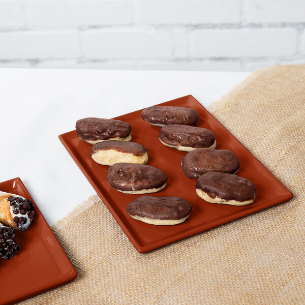 A Tablecraft copper cast aluminum rectangular cooling platter with chocolate covered pastries on it.