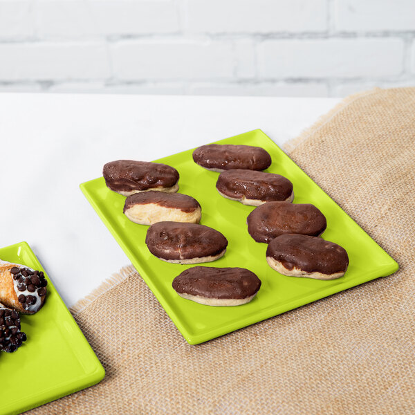 A lime green Tablecraft cast aluminum rectangular cooling platter with chocolate covered donuts and pastries on it.