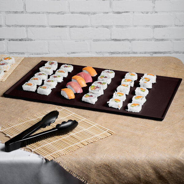 A Tablecraft Midnight Speckle cast aluminum rectangular cooling platter on a table with sushi and black tongs.