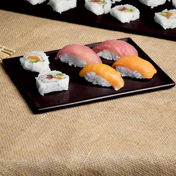 A Tablecraft midnight speckle rectangular cooling platter with sushi on a table.