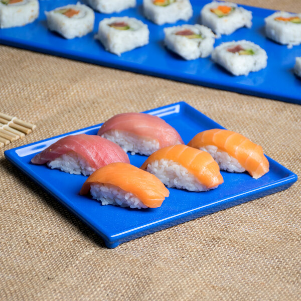 A Tablecraft blue speckle cast aluminum rectangular platter holding sushi on a table.