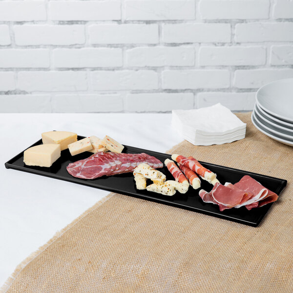 A Tablecraft black cast aluminum rectangular cooling platter with meat and cheese on it.