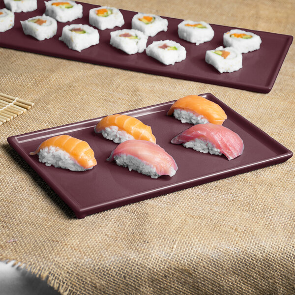 A Tablecraft maroon speckle cast aluminum rectangular cooling platter on a table with sushi.