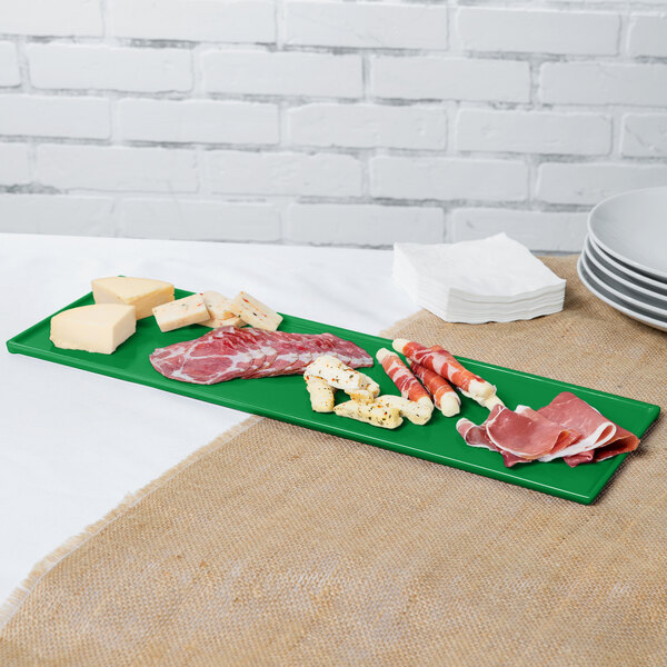 A green rectangular tray with different types of meats and cheese on it.