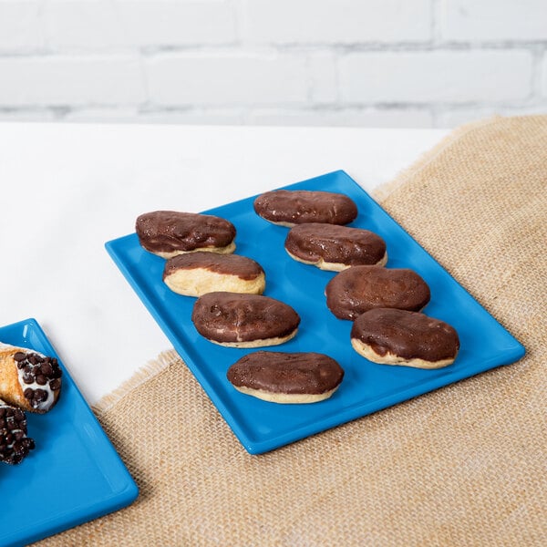 A chocolate covered doughnut and pastry on a sky blue Tablecraft rectangular cooling platter.