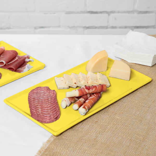 A Tablecraft yellow cast aluminum rectangular platter with meat and cheese on it.