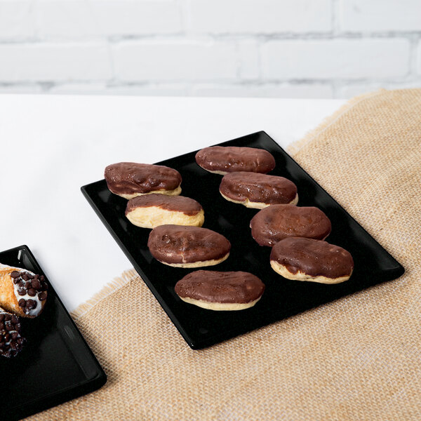 A black rectangular Tablecraft tray with chocolate covered pastries.