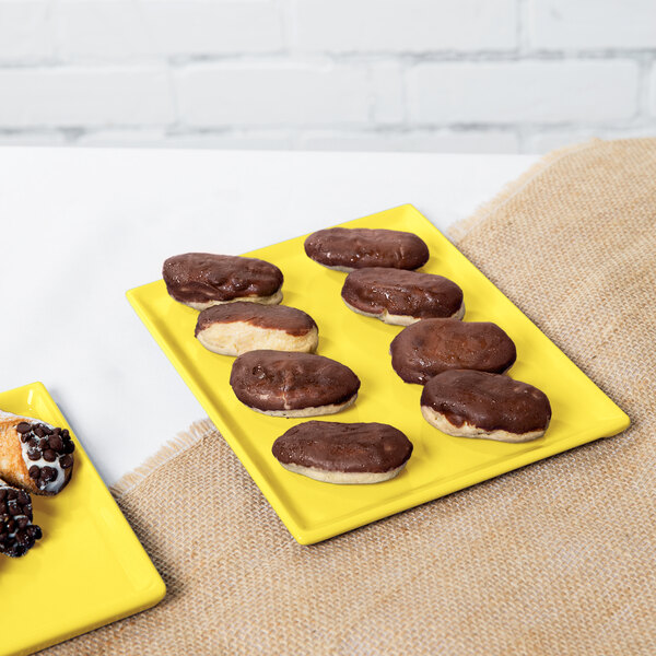 A chocolate covered doughnut on a yellow Tablecraft rectangular cooling platter.