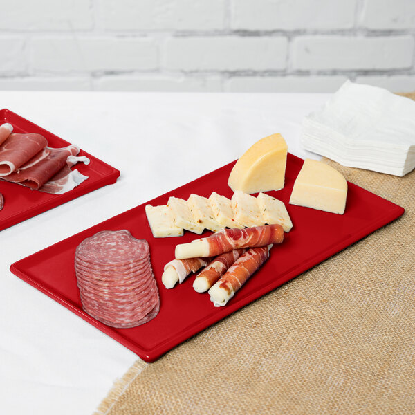 A Tablecraft red rectangular cast aluminum platter with meat and cheese on a table.