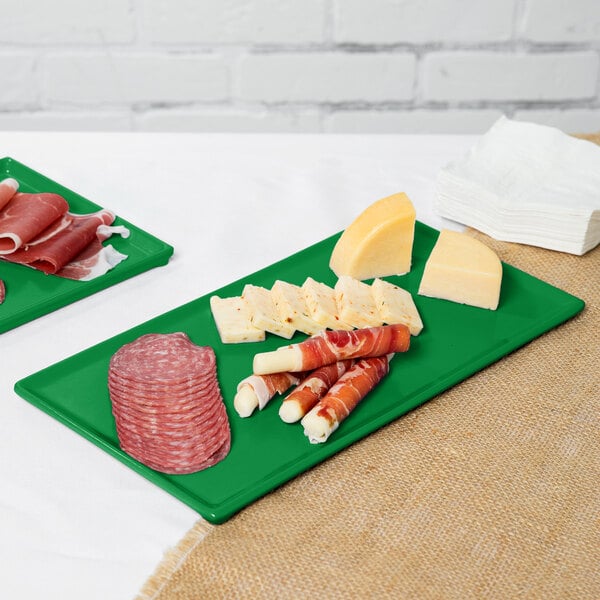 A slice of cheese on a green Tablecraft rectangular cooling platter.