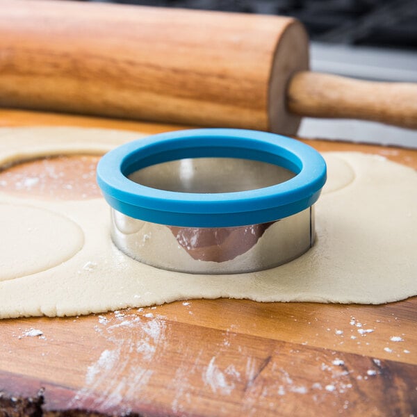A Wilton metal round cookie cutter with a blue comfort grip.