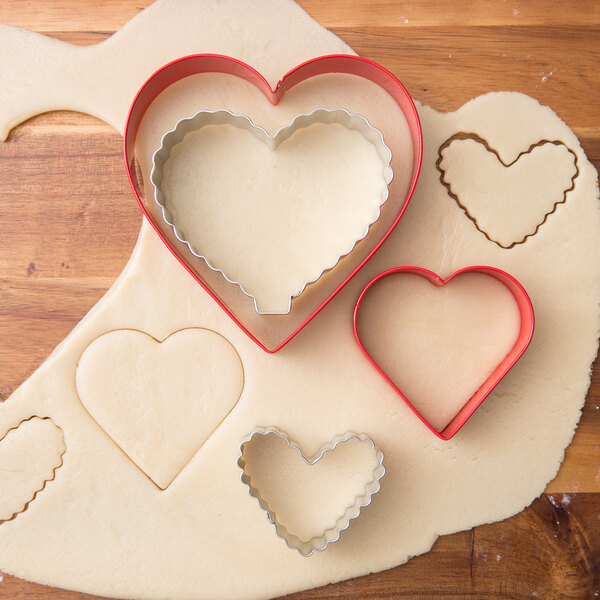 A set of Wilton heart shaped cookie cutters on a cutting board.