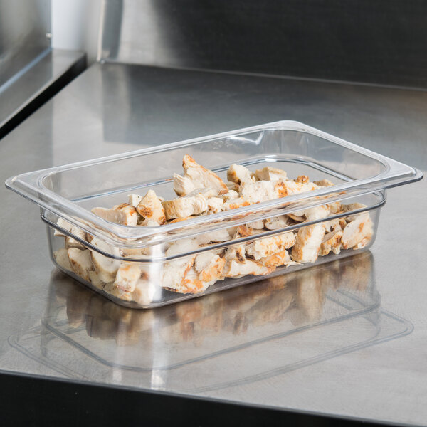 A clear Cambro food pan filled with food on a counter.