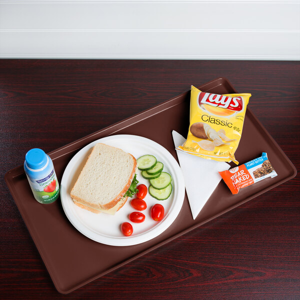 A Cambro dietary tray with a sandwich, chips, and a drink on it.