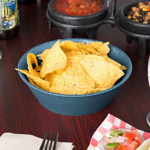 A blue polyethylene round basket filled with chips on a table.