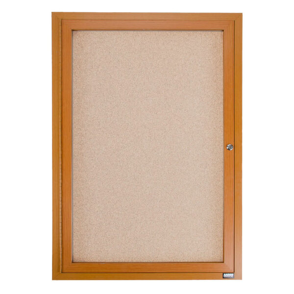 An enclosed cork bulletin board with a wooden frame and key.
