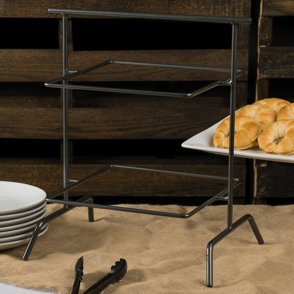 A Clipper Mill gray iron powder coated 2 tier square riser with plates of croissants on it.