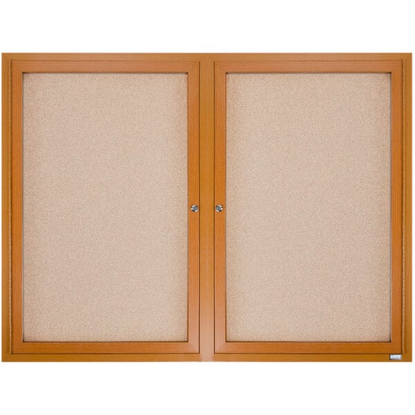 A natural oak framed Aarco enclosed bulletin board with cork interior.